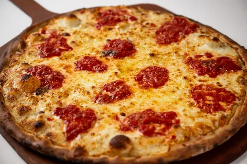 Close-up of a large coal fired pepperoni pizza with golden melted cheese and crispy crust, fresh from Anthony’s oven.