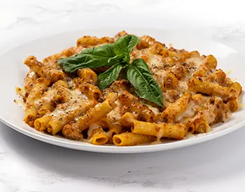 Baked ziti pasta with basils on top.