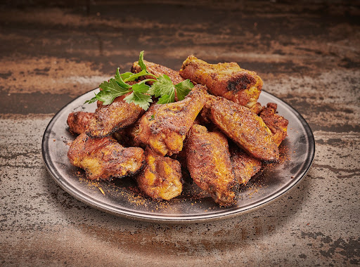 Plate of crispy chicken wings garnished with fresh parsley.