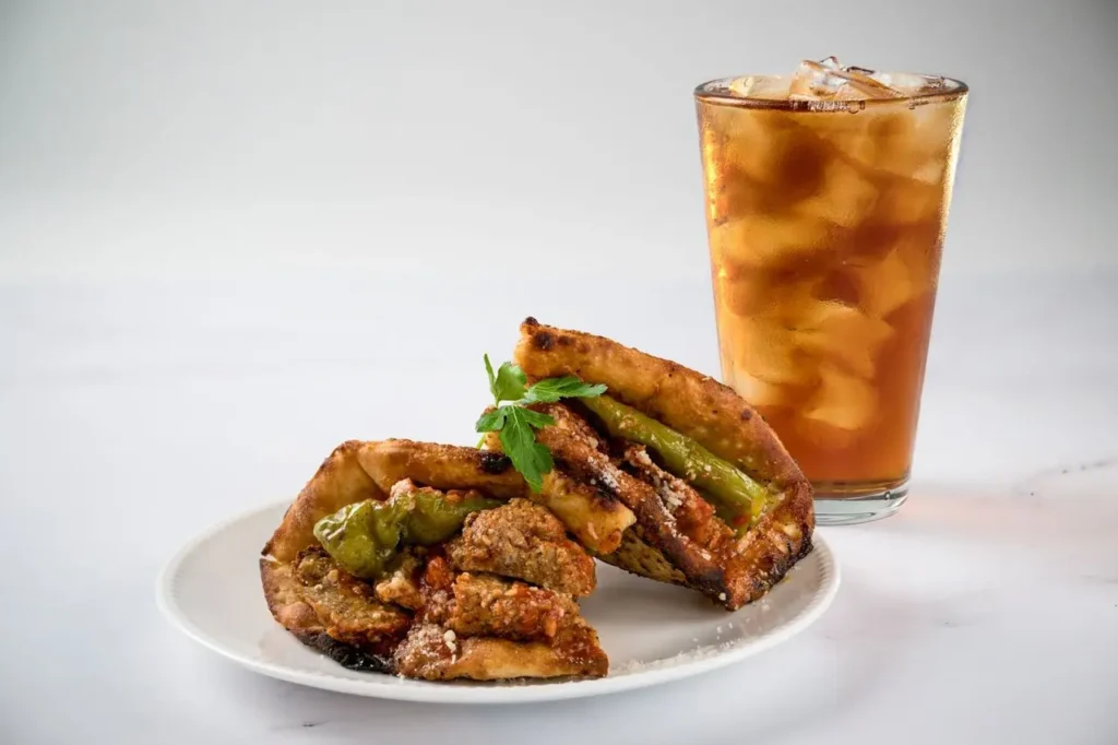 A meat-filled sandwich with fresh toppings and a cold Coke, perfect for lunch.