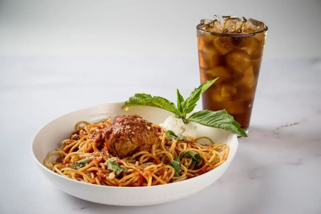A Spaghetti filled with savory meats, served with a cold Coke.