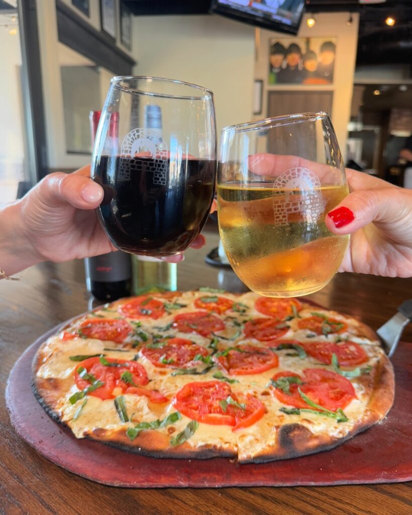 A couple enjoying pizza and drinks together at Anthony’s Coal Fired Pizza and Wings.