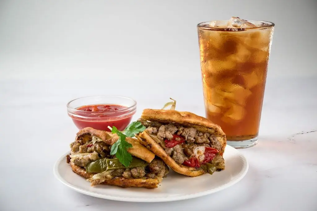 A tasty sandwich with seasoned fillings served alongside a chilled Coke.