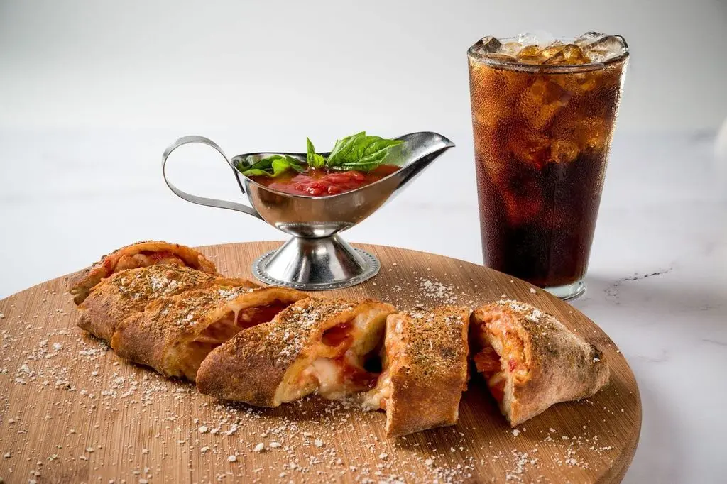 A delicious stromboli served with tomato sauce and a cold Coke, perfect for a satisfying meal.