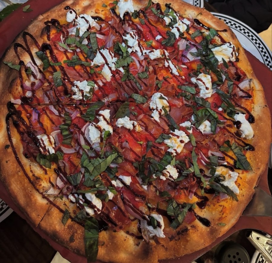 Coal‑fired pizza topped with fresh burrata and drizzled hot honey, showcasing glossy cheese and vibrant sauce for a midday treat.