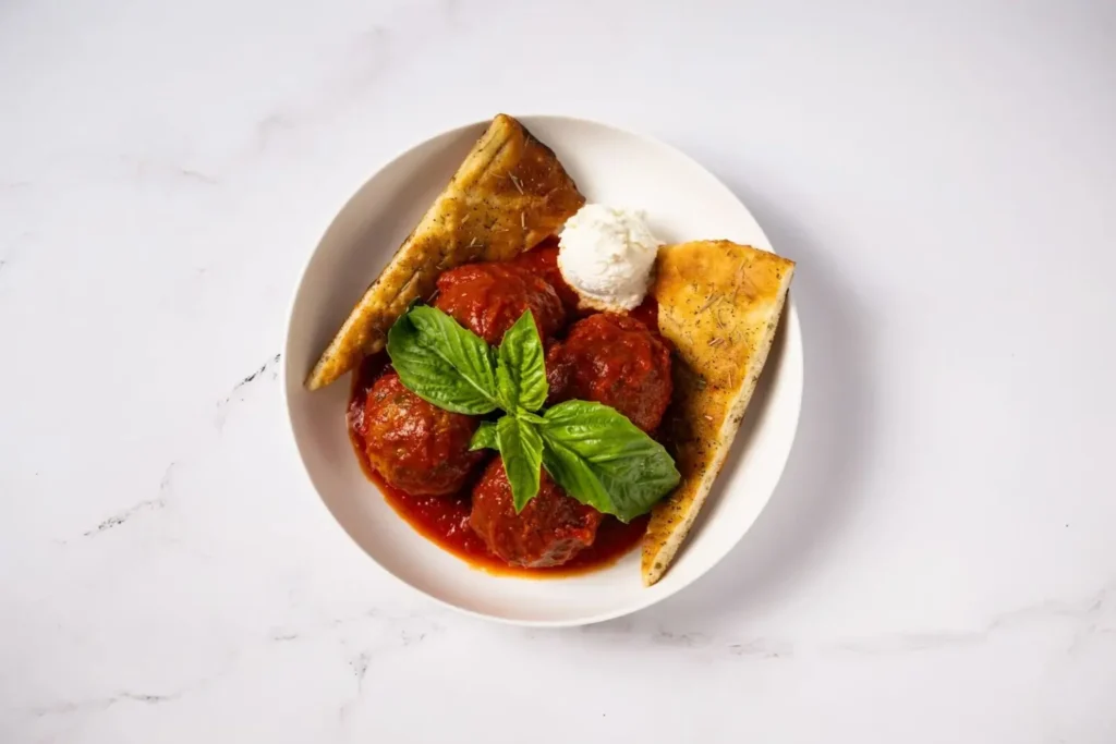 Close-up shot of Anthony’s Maria’s Meatballs in Italian plum tomato sauce, topped with creamy ricotta.