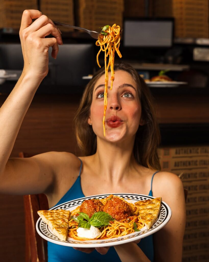 A woman enjoys a bite of Anthony’s Burrata and Prosciutto pasta, rich in flavor