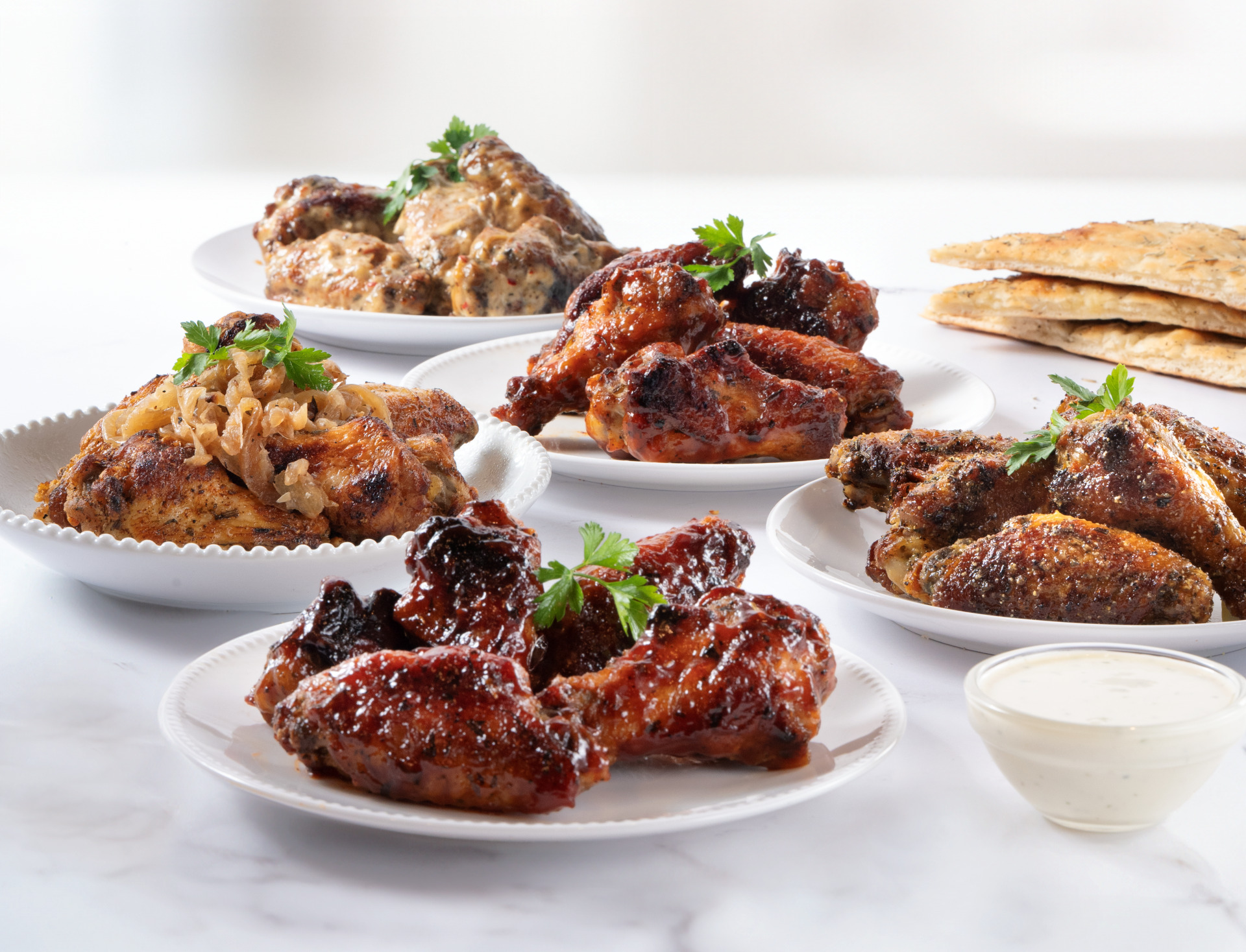 A shot of five plates of Anthony’s jumbo never-frozen chicken wings in different flavors.