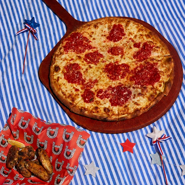 Anthony’s Coal Fired Pizza traditional pizza and wings on a patriotic Fourth of July picnic setup