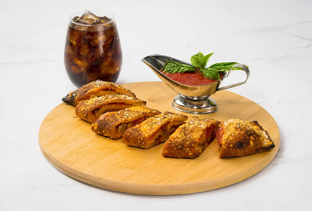 A delicious stromboli served with tomato sauce and a cold Coke, perfect for a satisfying meal.